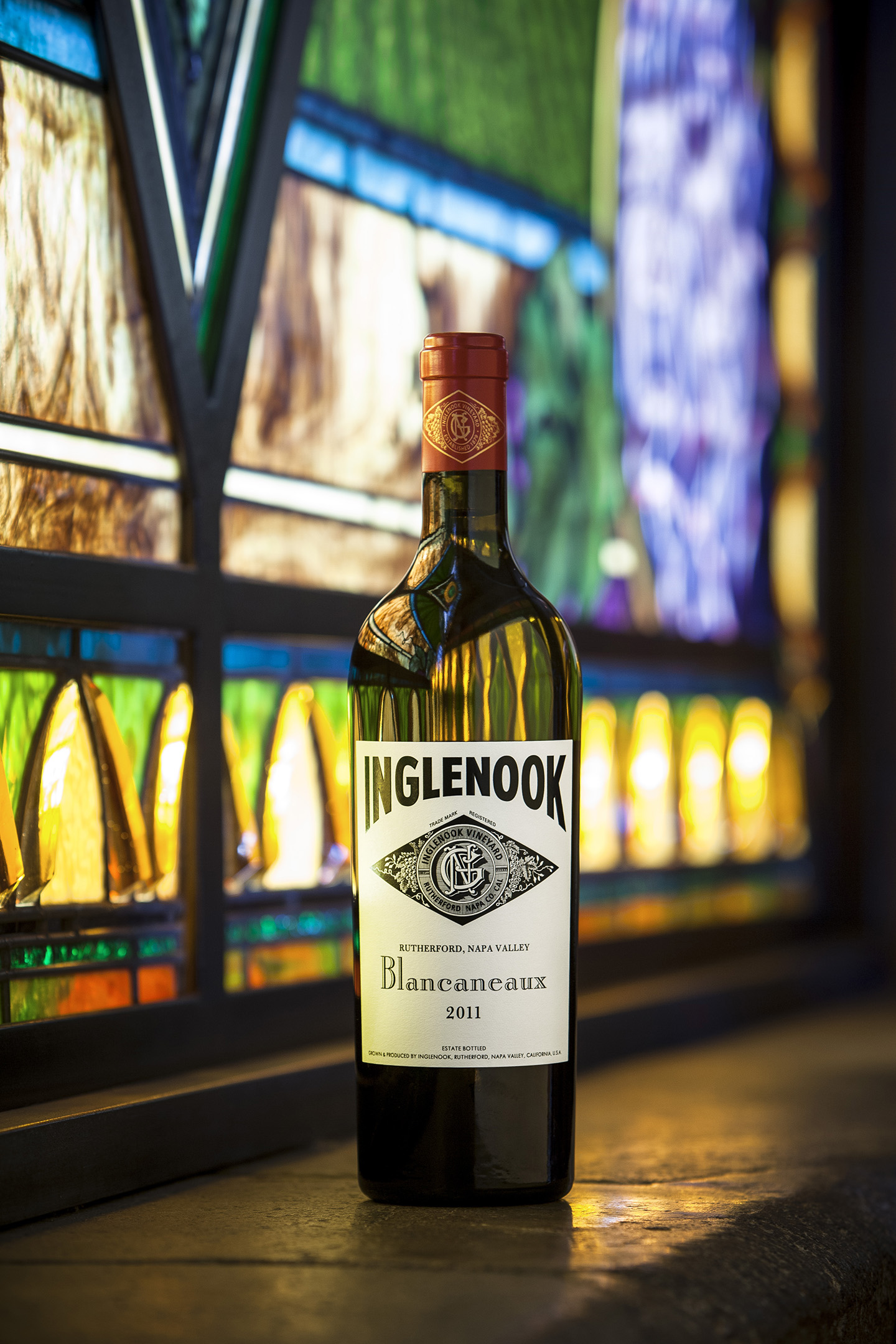 Bottle of Inglenook's Blancaneaux wine sitting on a cement ledge in front of a stained glass window