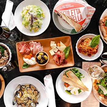 A table filled with many plates of different kinds of food made at Cafe Zoetrope.
