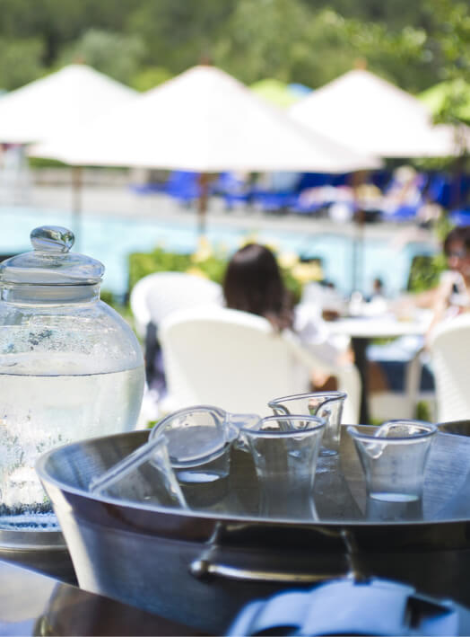 water carafes chilling in ice with pool in background.